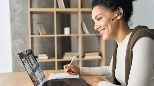 A woman sits in her home office while participating in a virtual interview on her laptop.